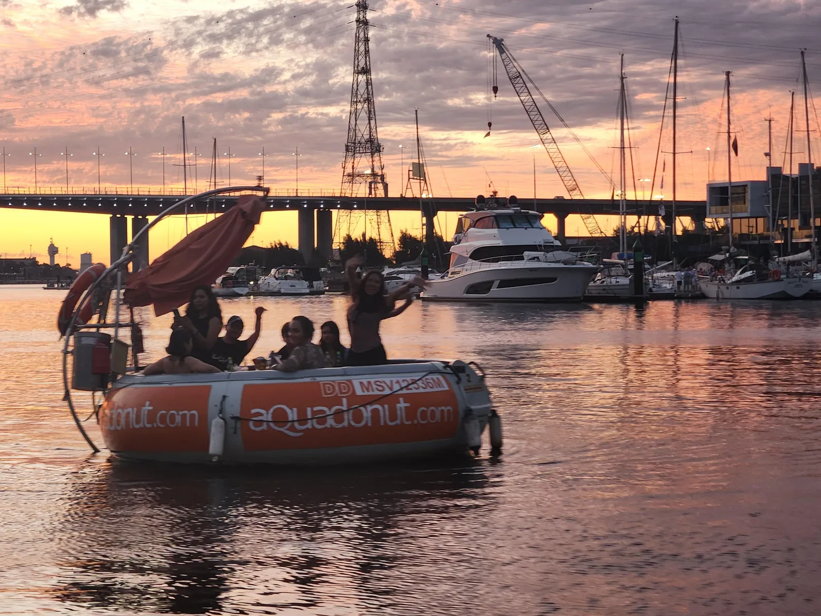 A round Aqua Donut BBQ boat at sunset in a Docklands marina