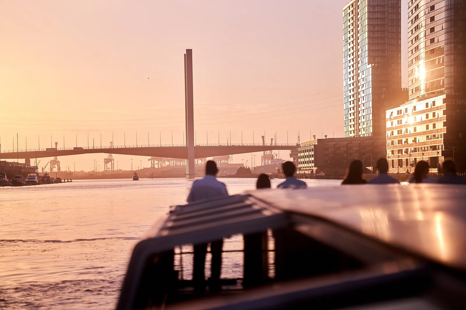Passengers at a cruise boat's bow watching the sunset over the Bolte Bridge