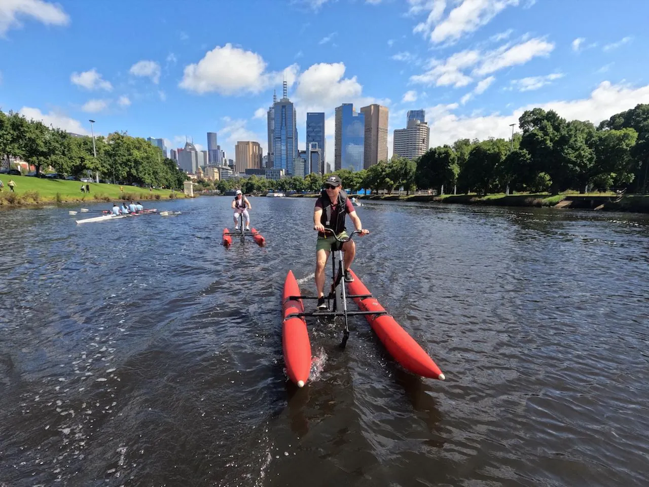 Waterbike riders pedalling up the Yarra toward the city skyline
