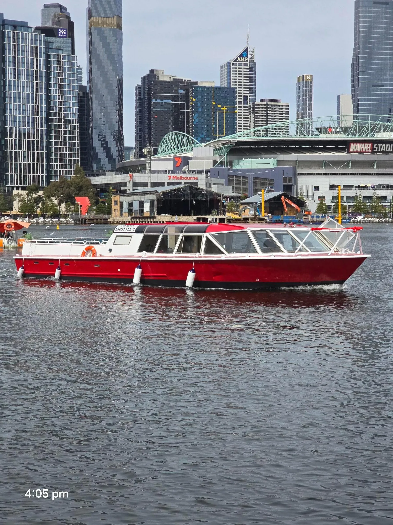 A red Yarra River Cruises boat on the river below the Southbank towers