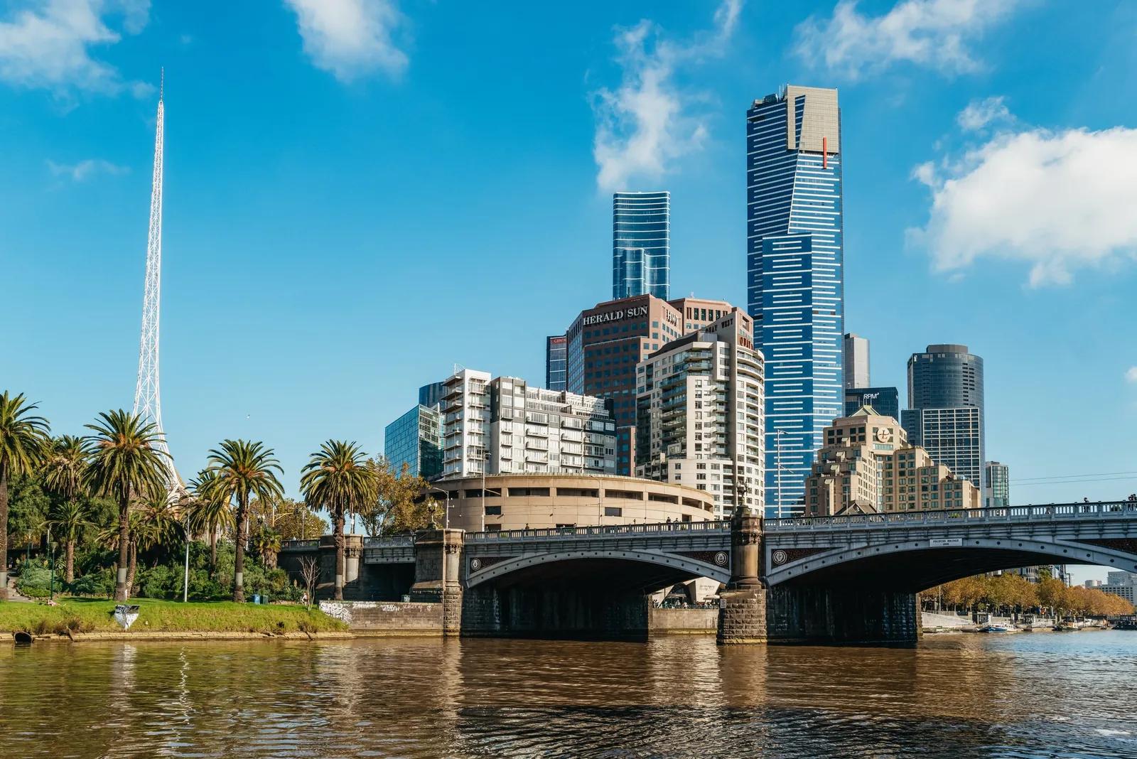 Princes Bridge and the Arts Centre spire beside the Yarra under a blue sky